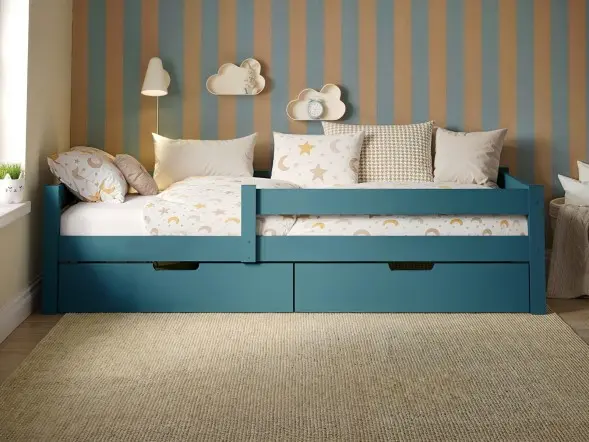 Wooden single bed with two pull-out storage drawers, styled in a neutral children’s bedroom with striped feature wall and soft patterned bedding