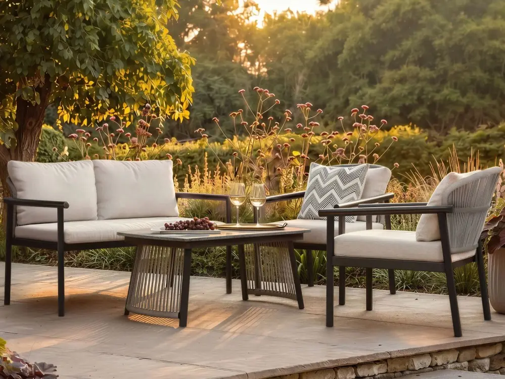 Four-piece garden sofa set with two armchairs, a two-seater sofa and coffee table on a patio at sunset
