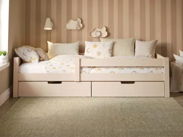 Wooden single bed with two pull-out storage drawers, styled in a neutral children’s bedroom with striped feature wall and soft patterned bedding