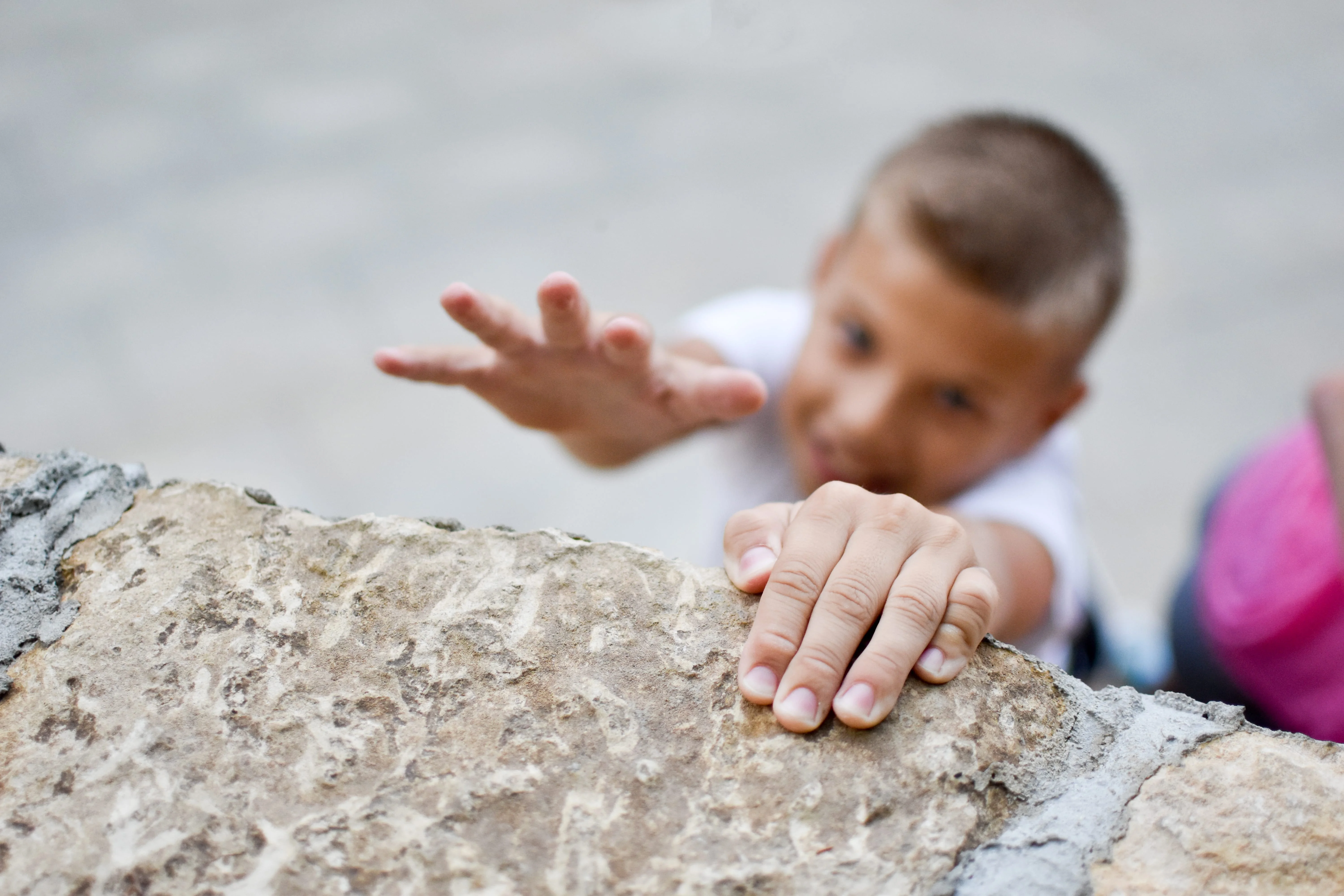 Boy child holds fingers edge wall falling off cliff