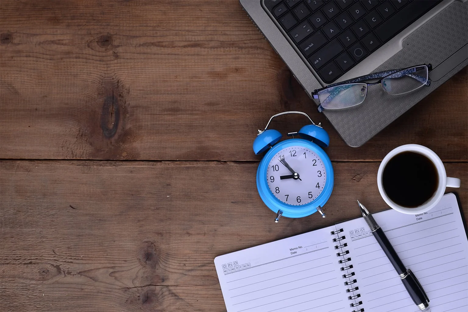 Workplace with notebook clock coffee laptop